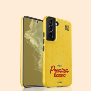 May include: A yellow phone case with a textured surface and the words "Premium Banana" in red script. The case also features a QR code and the text "550grams" and "ELIZABETH". The phone screen is visible.