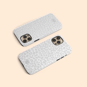 May include: Two white iPhone cases with a grey leopard print design. The cases have a raised camera bump and a cutout for the phone's buttons.