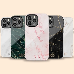 May include: Five different phone cases with marble patterns. The cases are white, black, green, pink, and white with gold accents. Each case has a different initial on the back.
