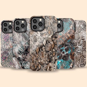 May include: A collection of five smartphone cases featuring various snake skin patterns in shades of pink, brown, tan, black, and turquoise. Each case has a camera cutout and some display the letters EK or AK in white text on the lower portion.