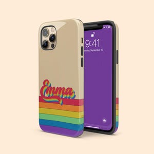 Może przedstawiać: Beige'owe etui na telefon z wzorem tęczowych pasków i imieniem "Emma" w retro czcionce. Etui jest przeznaczone do iPhone'a.