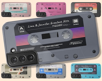 Puede incluir: Una funda de smartphone gris con un diseño de casete retro que incluye el texto Liam & Jennifer Greatest Hits 11.8.2007, A Side, C60 y Compact Cassette. La funda tiene un recorte para la cámara y está rodeada de otras fundas de casete de colores.