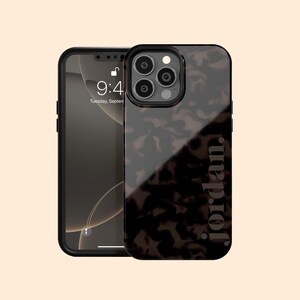 Op de afbeelding: Een zwarte iPhone met een hoesje met schildpadpatroon. Op de hoes staat de naam "jordan" verticaal in een lichtgrijze lettertype. Het telefoonscherm toont de tijd als 9:41 uur op dinsdag 7 september.