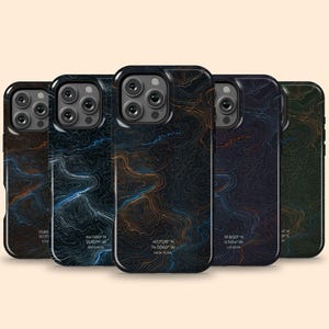 May include: A collection of five phone cases with a topographic map design. The cases feature a dark background with orange, blue, and white contour lines. Coordinates and city names are printed on some cases.