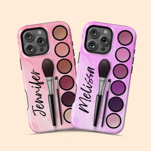 May include: Two phone cases with a makeup theme. One is pink with the name "Jennifer" and the other is purple with the name "Melissa". Each case features a makeup palette design with brushes.