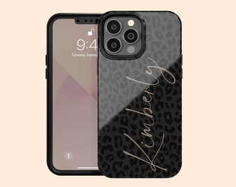 May include: A smartphone case featuring a dark grey and black leopard print pattern with the name Kimberly written in a light-coloured cursive script across the back. The case has a cutout for a triple-lens camera system on the upper left corner.