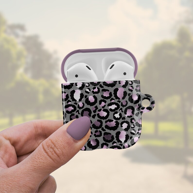 May include: A pink and gray leopard print phone case with a purple lid for Apple AirPods.