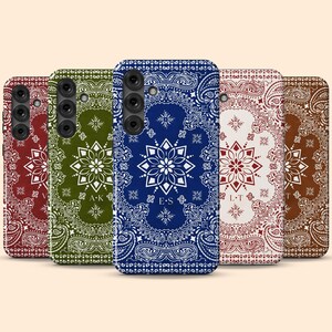 May include: A collection of phone cases with a paisley bandana design. The cases are in various colors, including red, green, blue, white, and brown. Each case features a central floral design and initials.