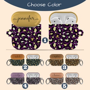 May include: AirPods case covers with different leopard print designs. The covers are available in purple, teal, brown, lavender, and white. The covers have a gold, brown, or purple trim. The covers have a small metal ring on the side. The covers have a name written on the top of the case. The names are Jennifer, Isabella, Sophia, Evelyn, and Lauren.