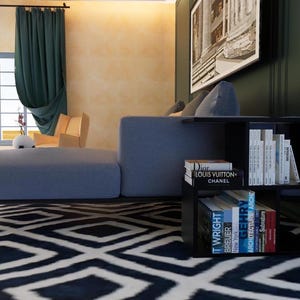 May include: A black side table with four shelves, holding a stack of books. The books have titles like "Dior", "Louis Vuitton", "Chanel", "T. Wright", "Breuer", "New York", "Architecture", "Century", and "Spectrum".