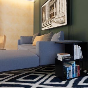 May include: A blue sectional sofa with a black metal frame sits in a living room with a black end table. The end table has three shelves filled with books, including one with the text "Louis Vuitton Chanel".