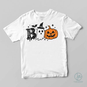 May include: White t-shirt with a black and orange Halloween design. The design includes a ghost, a pumpkin, a bat, and a spider web. The text "BOO" is implied by the design.