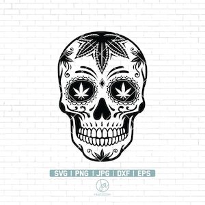 Peut inclure: Crâne de sucre noir et blanc avec des motifs de feuilles de marijuana dans les yeux. Le crâne présente des motifs floraux complexes autour des yeux et de la bouche.