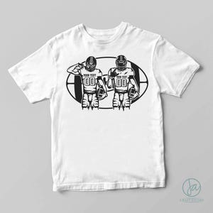 May include: White t-shirt with a black and white graphic of two football players in a football field. The text "YOUR TEXT" is on the jerseys of the players.