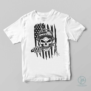 May include: A white t-shirt with a black and white graphic of a skull wearing a welding helmet and holding a welding torch. The skull is in front of a distressed American flag.
