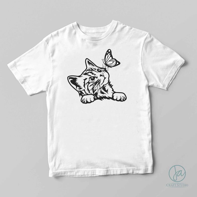May include: A white t-shirt with a black and white illustration of a kitten looking up at a butterfly.