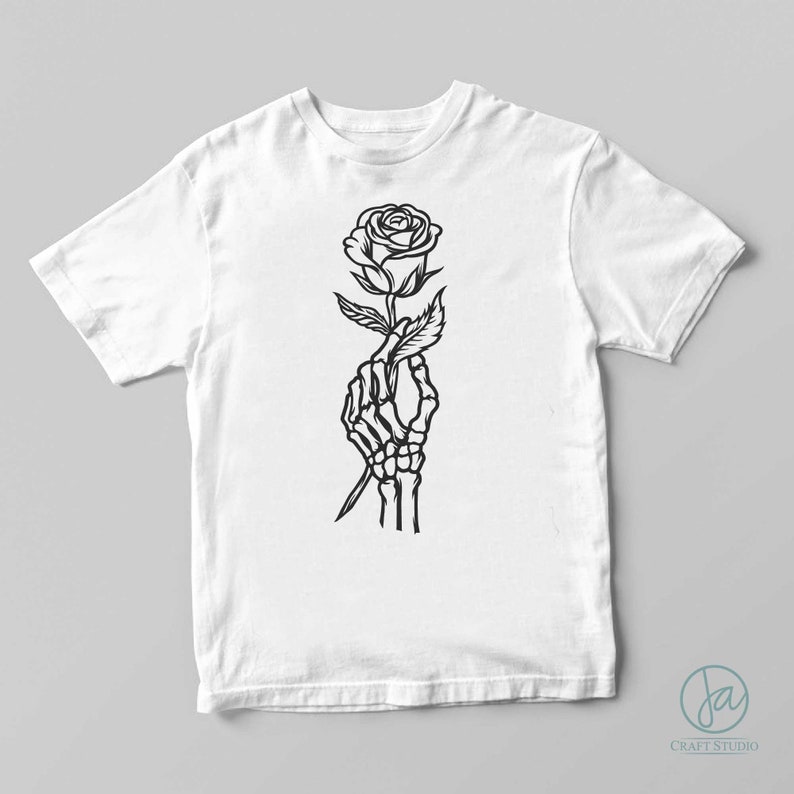 May include: A white t-shirt with a black line drawing of a skeleton hand holding a rose.