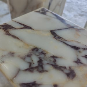 May include: Close-up of a white marble surface with brown and gray veining. The marble has a smooth, polished finish.