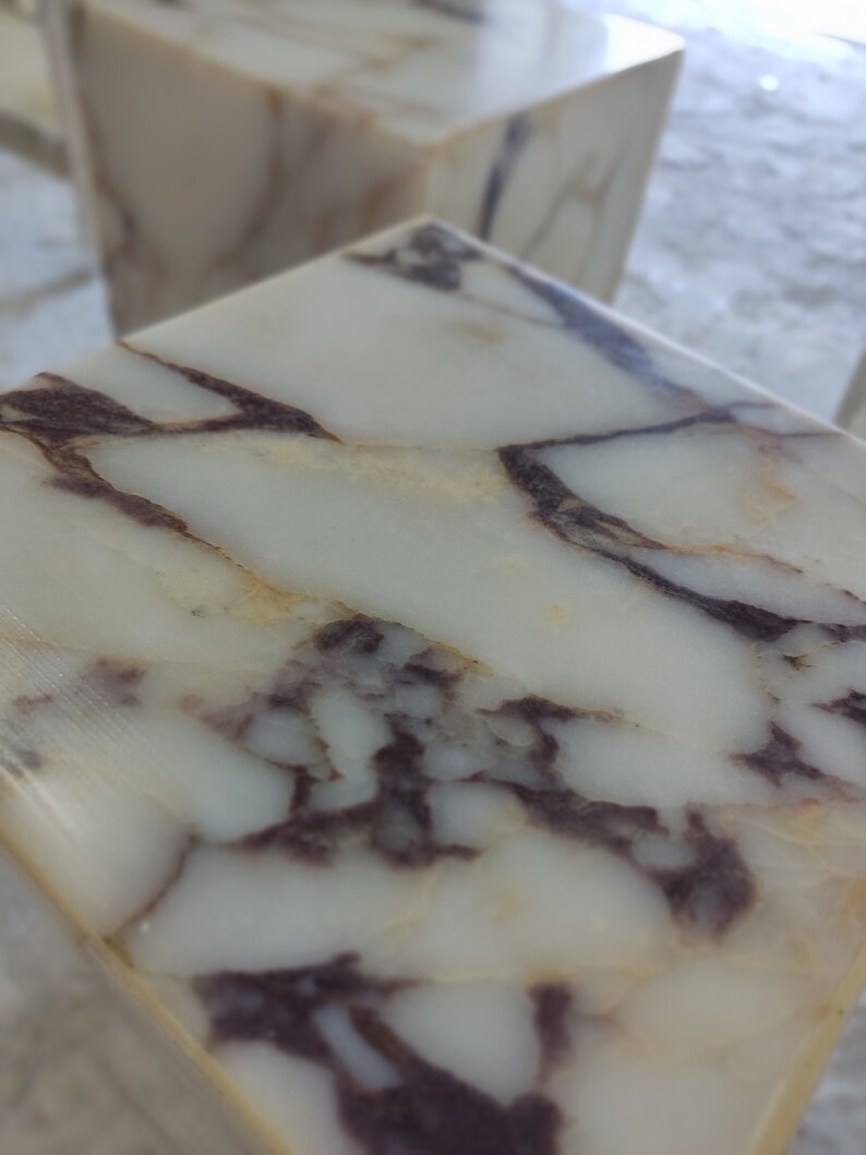 May include: Close-up of a white marble surface with brown and gray veining. The marble has a smooth, polished finish.