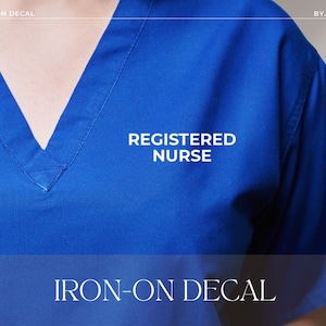 May include: A royal blue scrub top with the words "REGISTERED NURSE" in white. The text "IRON-ON DECAL" is displayed at the bottom. The top features a V-neck design.