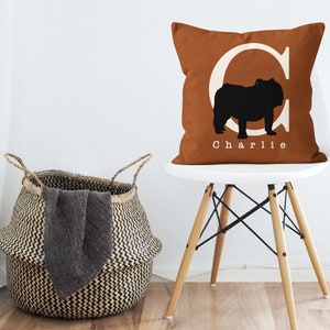 May include: A brown throw pillow with a white letter C and a black silhouette of a bulldog. The pillow has the name "Charlie" printed in white below the bulldog.
