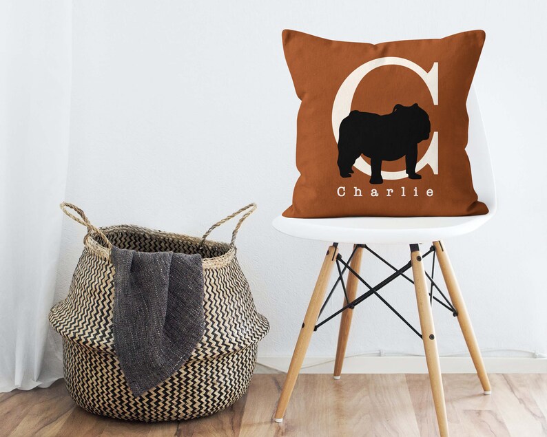 May include: A brown throw pillow with a white letter C and a black silhouette of a bulldog. The pillow has the name "Charlie" printed in white below the bulldog.