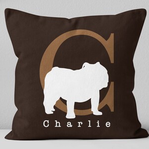 May include: Brown throw pillow with a white silhouette of a bulldog and the letter "C" in brown. The text "Charlie" is printed below the bulldog.