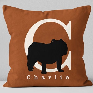 May include: A brown throw pillow with a white letter C and a black silhouette of a bulldog. The pillow has the name "Charlie" printed in white letters.