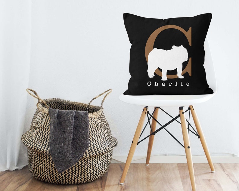 May include: Black and white pillow with a brown letter C and a white silhouette of a bulldog. The pillow has the name "Charlie" printed on it.