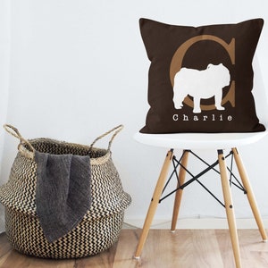 May include: A brown throw pillow with a white silhouette of a bulldog and the letter "C" in a brown font. The pillow has the name "Charlie" printed in white below the bulldog.