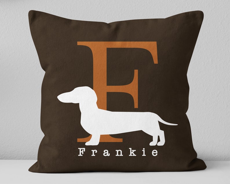 May include: Brown throw pillow with a white dachshund silhouette and the letter "F" in orange. The name "Frankie" is printed in white below the dachshund.