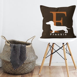 May include: A brown throw pillow with a white dachshund silhouette and the letter "F" in orange. The pillow has the name "Frankie" printed on the bottom.