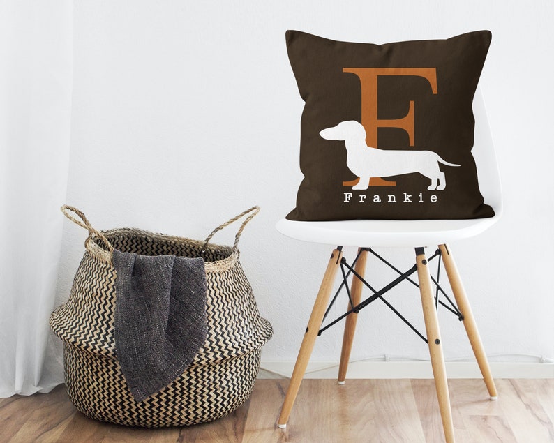 May include: A brown throw pillow with a white dachshund silhouette and the letter "F" in orange. The pillow has the name "Frankie" printed on the bottom.