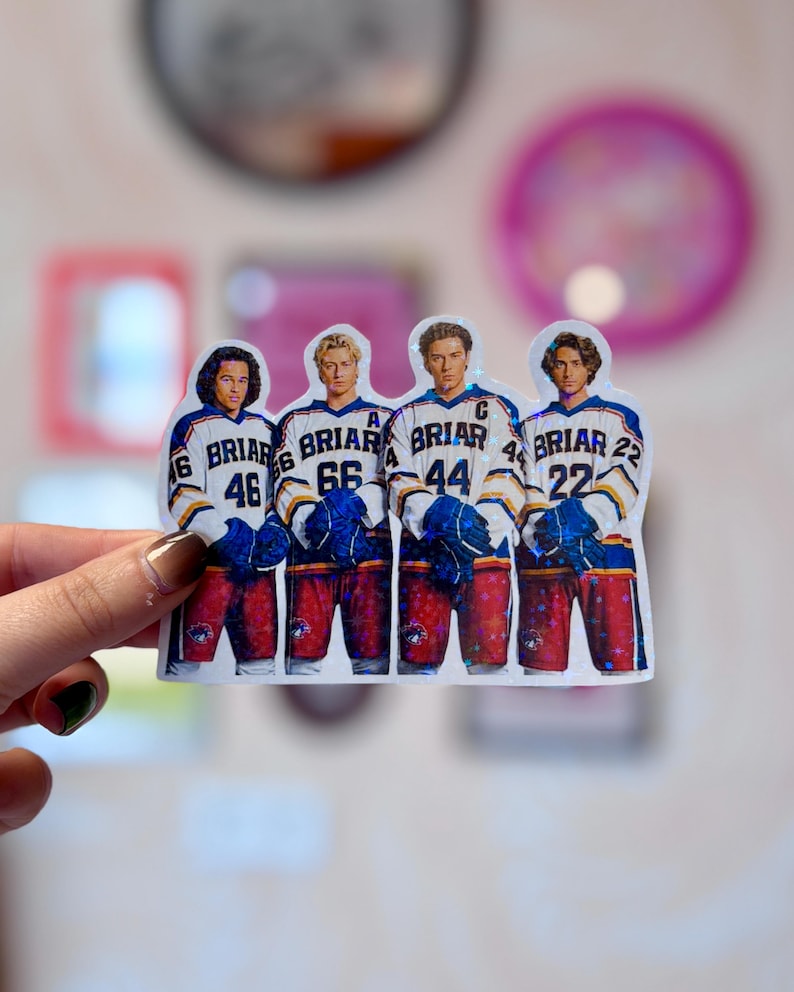 Pode incluir: Um adesivo hologr&aacute;fico com quatro jogadores de h&oacute;quei lado a lado. Cada jogador veste uma camisa branca com detalhes em azul e amarelo, a palavra BRIAR e os n&uacute;meros 46, 66, 44 e 22. Eles usam luvas azuis e cal&ccedil;&otilde;es vermelhos.