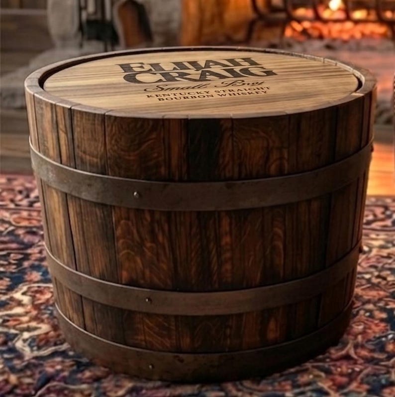 May include: A wooden barrel-shaped side table with the text "Elijah Craig Small Batch Kentucky Straight Bourbon Whiskey" printed on the top. The table is made of dark wood and has metal bands around it.