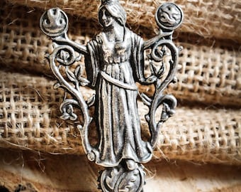 May include: Silver pendant necklace featuring a stylized female figure standing within a circular frame of vines and leaves. The figure is wearing a long flowing robe and a crown.