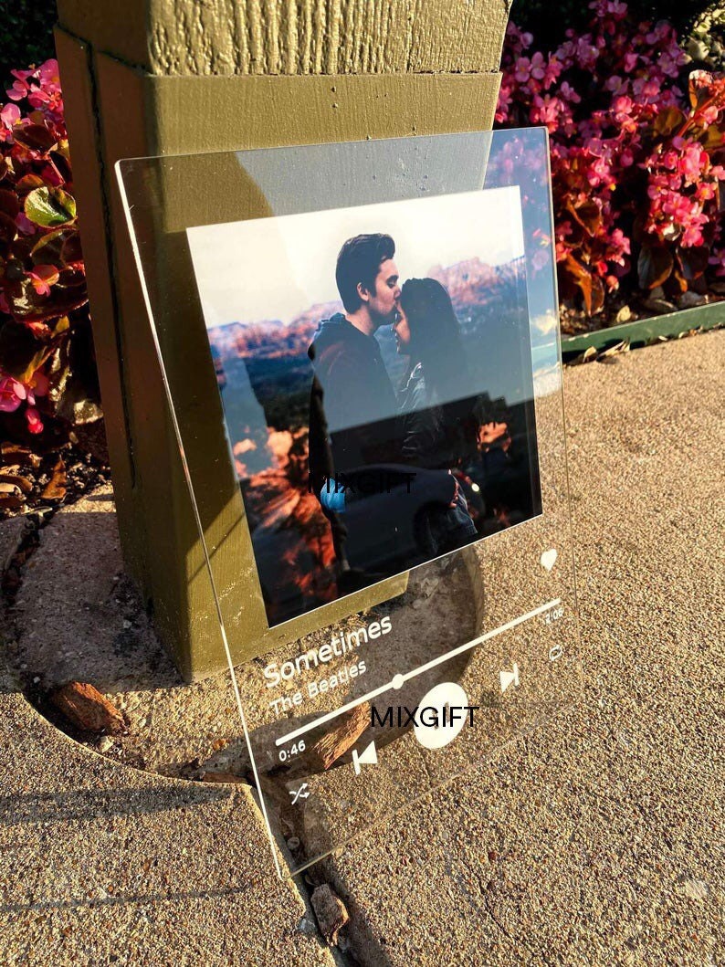 May include: A clear acrylic photo frame featuring a couple embracing, with a music player interface design. The text "Sometimes" by The Beatles is displayed, along with the time 0:46 and the logo "MIXGIFT".