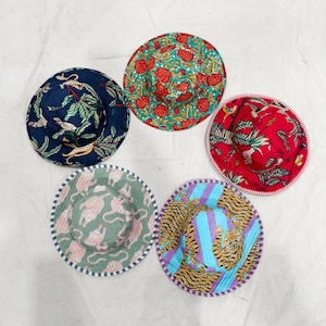 May include: Five colorful, patterned sun hats. Designs include floral, jungle, and animal prints in various colors like red, blue, green, and purple. Each hat has a contrasting trim.