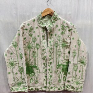May include: Cream-colored jacket with green embroidered floral and elephant designs. The jacket features a high collar and a striped green and white lining. The embroidery includes flowers, birds, and elephant figures.