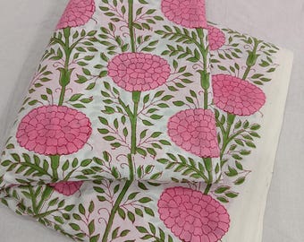 May include: A folded piece of white fabric featuring a repeating pattern of large pink flowers with green stems and leaves. The floral design is arranged in vertical rows across the textile, showcasing a clear botanical print on a light background.