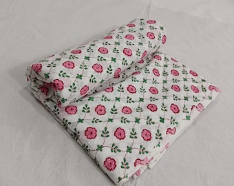 May include: White cotton fabric with a pink and green floral print. The fabric is folded in half and the print is visible on both sides.