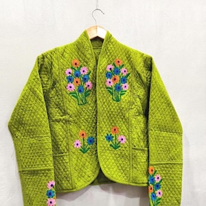 Pode incluir: Uma jaqueta acolchoada verde-limão com frente aberta e gola mandarim. A peça é decorada com motivos florais bordados em rosa, azul e laranja no peito, nos painéis frontais inferiores e ao longo dos punhos das mangas compridas.