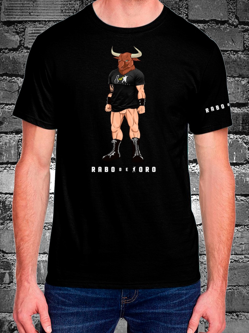 May include: Black t-shirt with a graphic of a bull-headed man wearing a black t-shirt with the text "Rabo de Oro" printed on the front. The text "Rabo de Oro" is also printed on the right sleeve of the shirt.