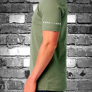 May include: A green short-sleeved t-shirt with the text "RABO DE TORO" printed on the sleeve.