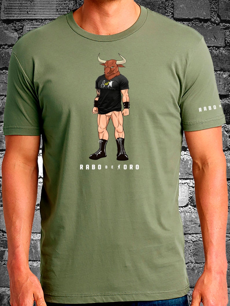 May include: A green t-shirt with a graphic of a bull-headed wrestler wearing black boots and a black t-shirt with the text "RABO DE ORO". The text "RABO DE ORO" is also printed on the bottom of the shirt.