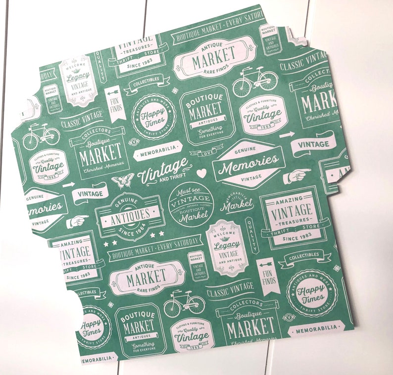 Puede incluir: Papel estampado en verde y blanco con varios dise&ntilde;os tem&aacute;ticos de mercado vintage. El papel presenta texto como "Boutique Market", "Vintage", "Antiques", "Happy Times", "Amazing Vintage", "Genuine Memories", "Must See Vintage Boutique Market", "Collectibles", "Memorabilia", y "Classic Vintage".