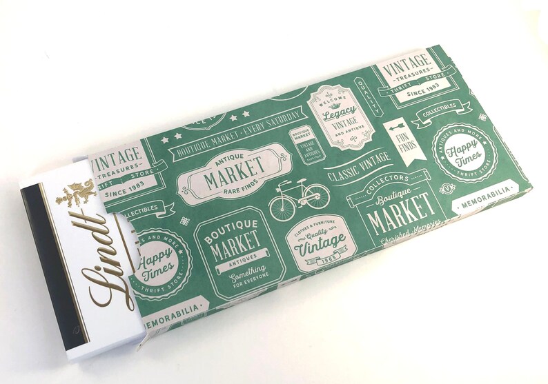 Puede incluir: Un papel de regalo verde y blanco con un tema de mercado vintage. El papel presenta una bicicleta, texto que dice "Boutique Market" y las palabras "Classic Vintage".