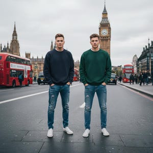 Peut inclure: Deux personnes vêtues de tenues décontractées posent dans une rue de Londres. L'une porte un sweat-shirt bleu marine, l'autre un sweat-shirt vert, tous deux avec des jeans bleus et des baskets blanches. En arrière-plan, des bus rouges et Big Ben.