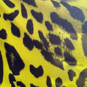 Puede incluir: Primer plano de una tela amarilla con un estampado de leopardo negro.