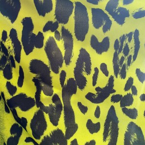 Puede incluir: Primer plano de una tela amarilla con un patr&oacute;n de estampado de leopardo negro.